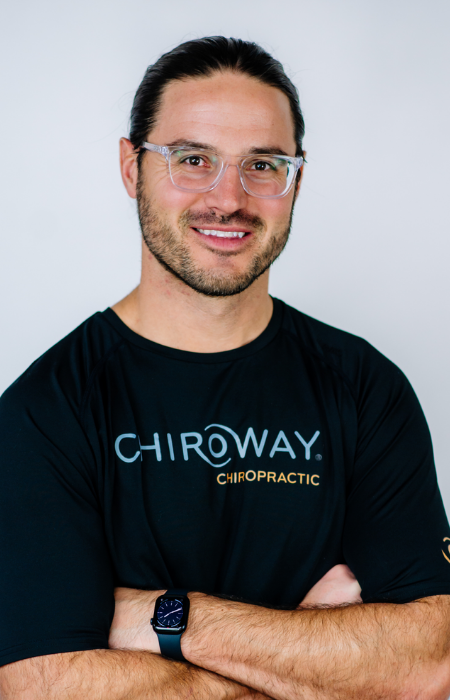 Dr. Trent Scheidecker, founder of ChiroWay, smiling confidently in a professional setting. His passion for chiropractic care began in high school and now fuels his mission to make wellness accessible through regular chiropractic adjustments.